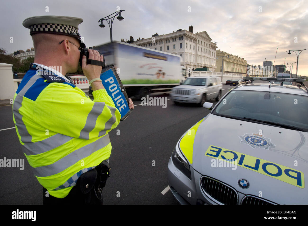 A police officer using a handheld laser camera on a city road to catch speeding motorists Stock Photo