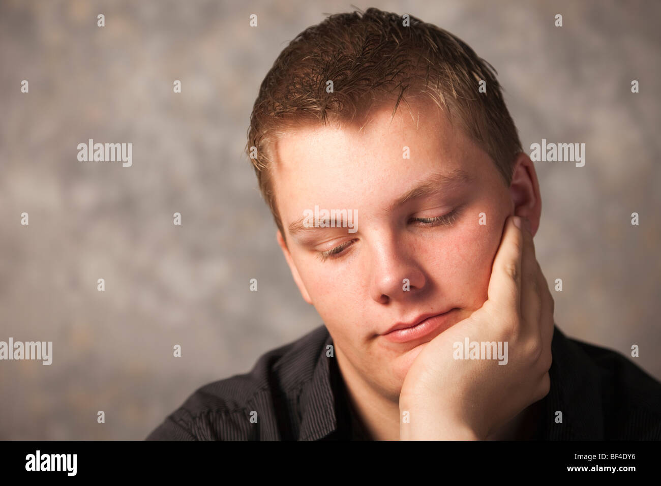 Young man thinking with a pensive bored expression resting chin on hand