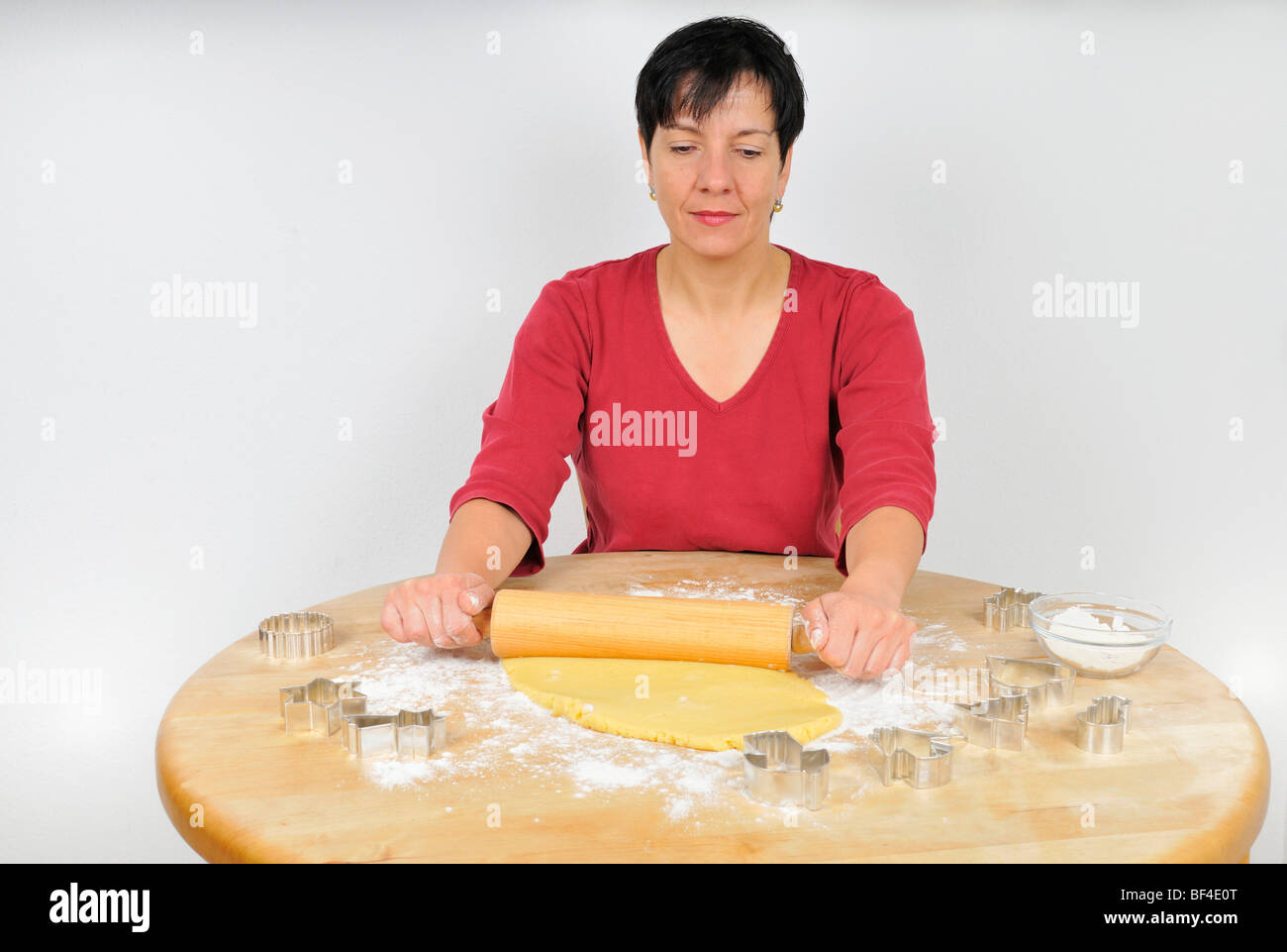 Christmas baking, woman rolling out the dough for Christmas cookies with a rolling pin, cookie cutters are lying on the table Stock Photo