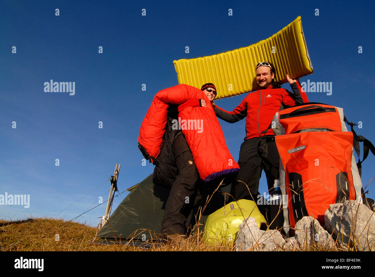 Hikers, young man and woman having fun while putting up a bivouac with tent, sleeping bag, backpack and sleeping pad, Heidachst Stock Photo