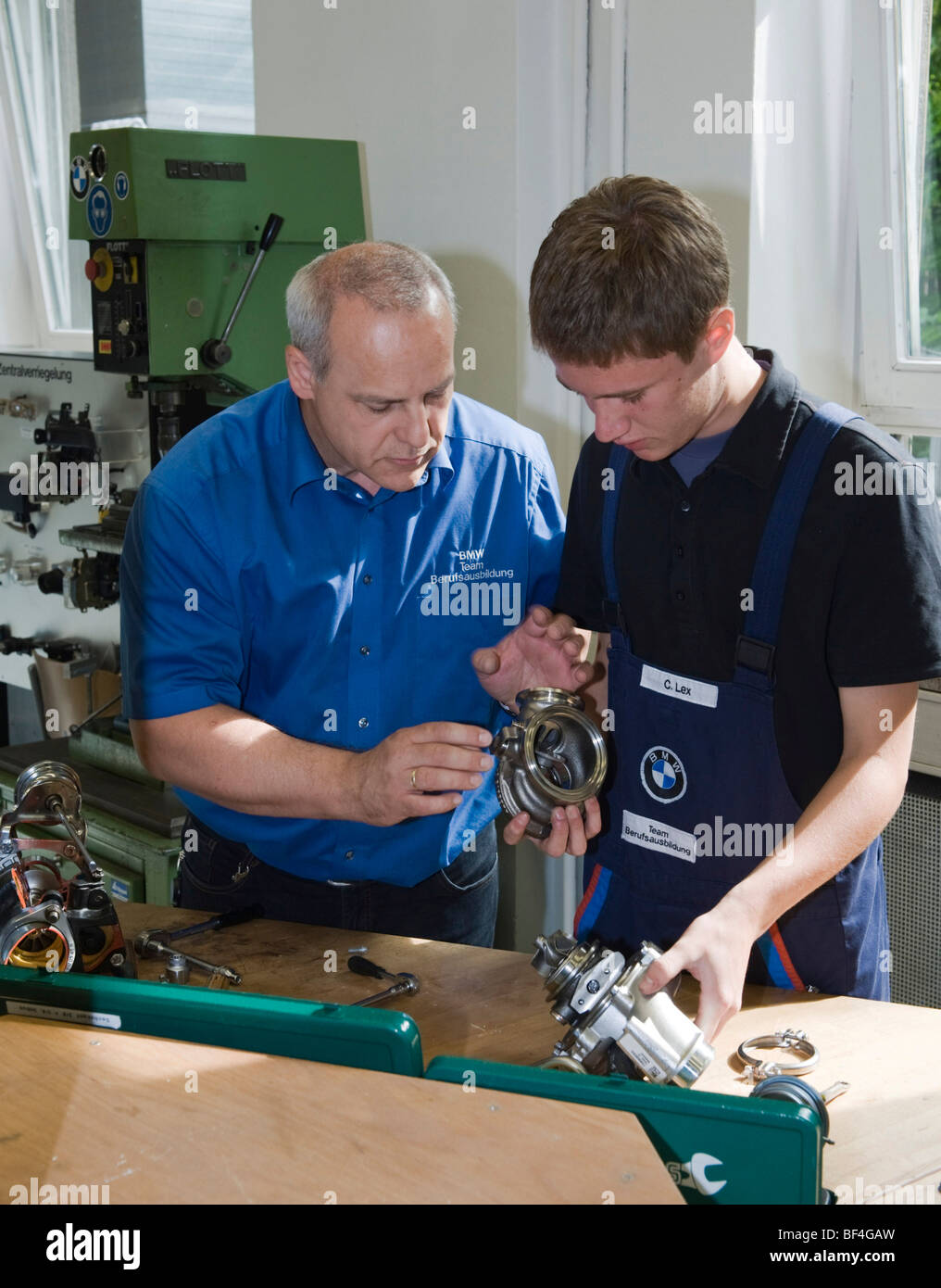 Master explaining to an apprentice while working on part of an engine in the BMW training center for automotive mechatronics, M Stock Photo