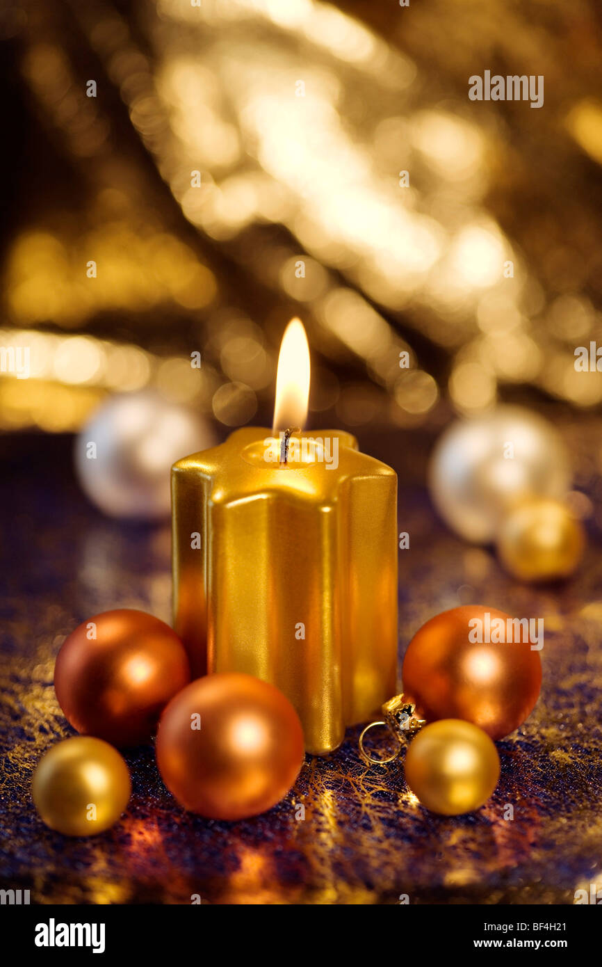 Burning golden candle with baubles for the Christmas tree Stock Photo