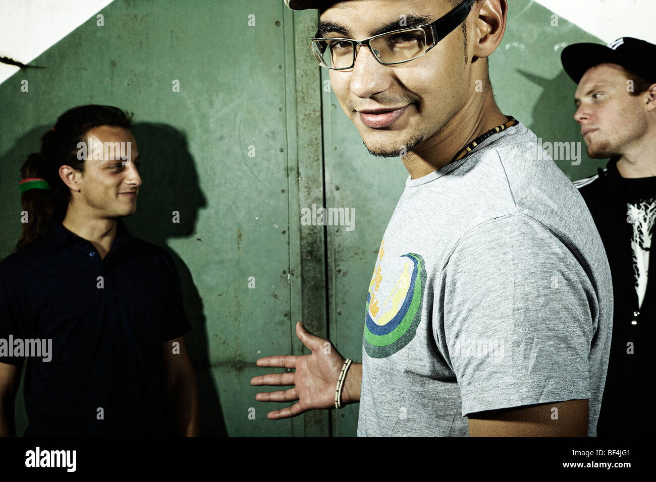 Portrait of three young men standing in front of an old steel door ...