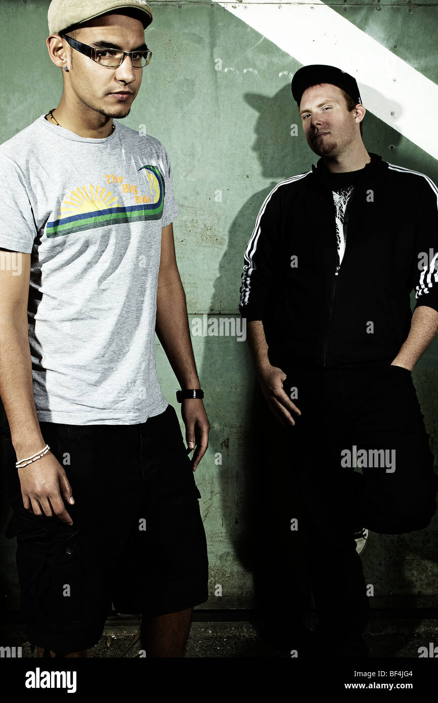 Portrait of two young men standing in front of an old steel door, cool ...