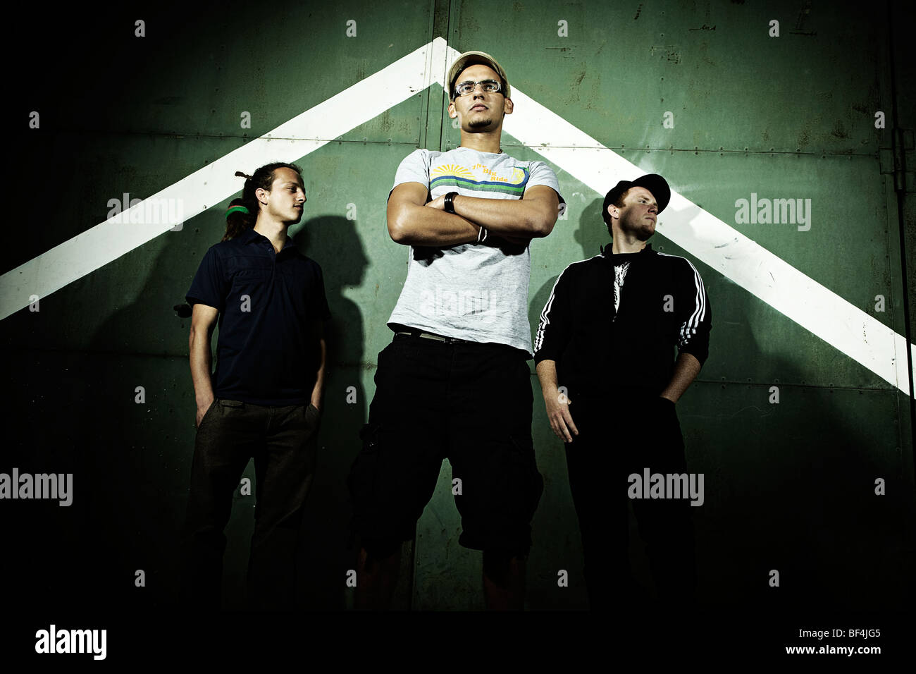 Portrait of three young men standing in front of an old steel door ...