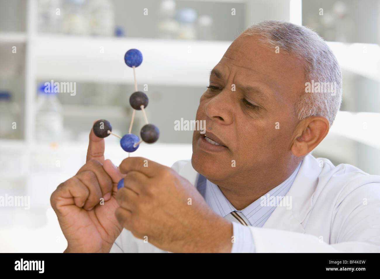 African scientist viewing molecule model in laboratory Stock Photo