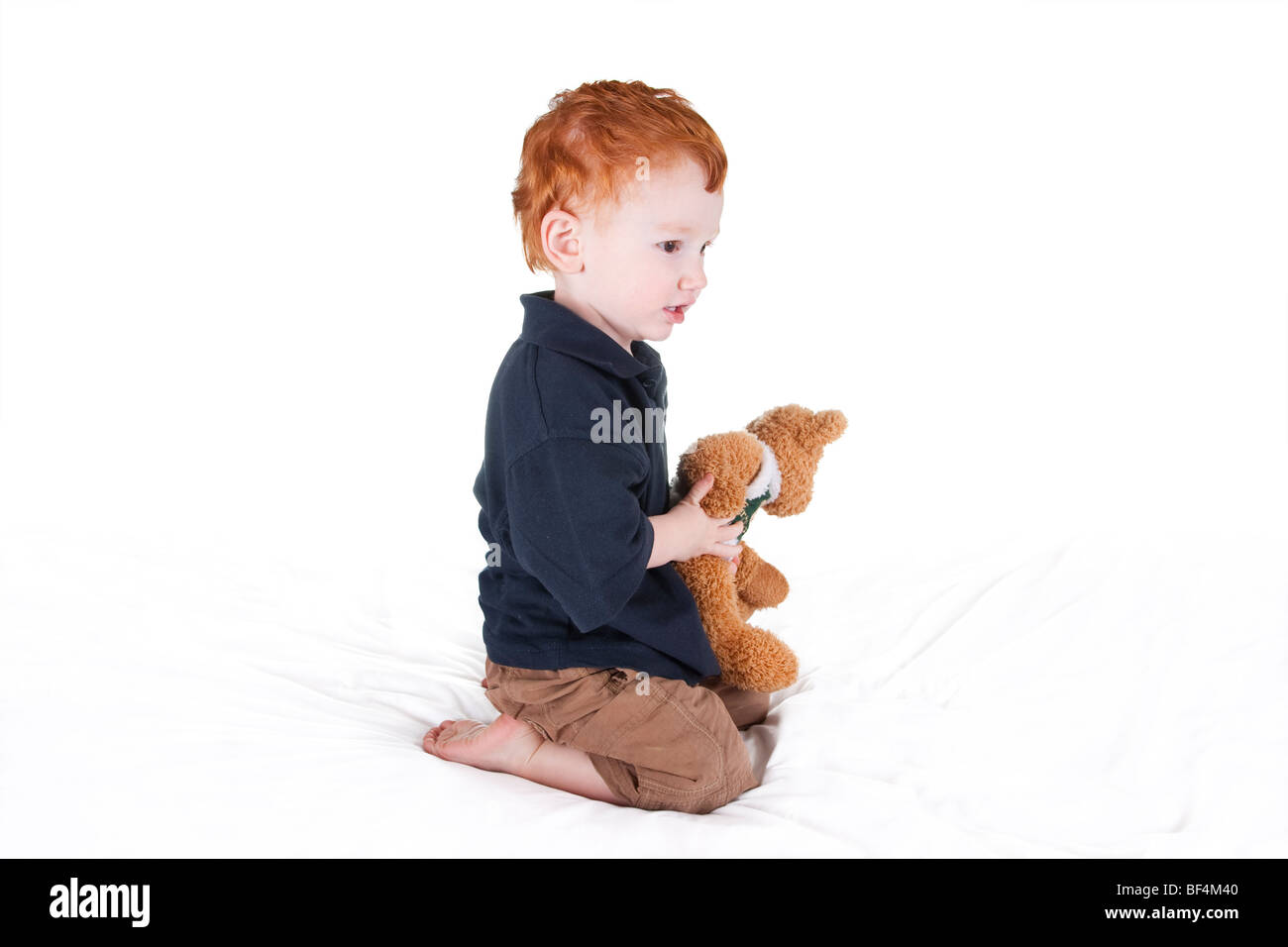 Young boy holding teddy bear and looking intently ahead Stock Photo - Alamy