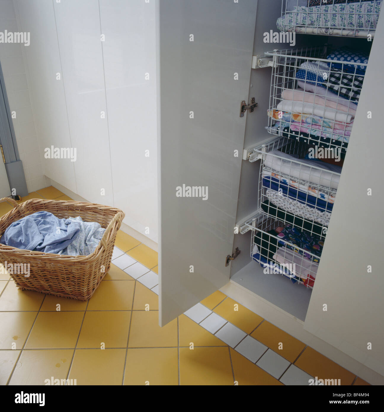 Utility room with basket of washing beside cupboard with folded laundry
