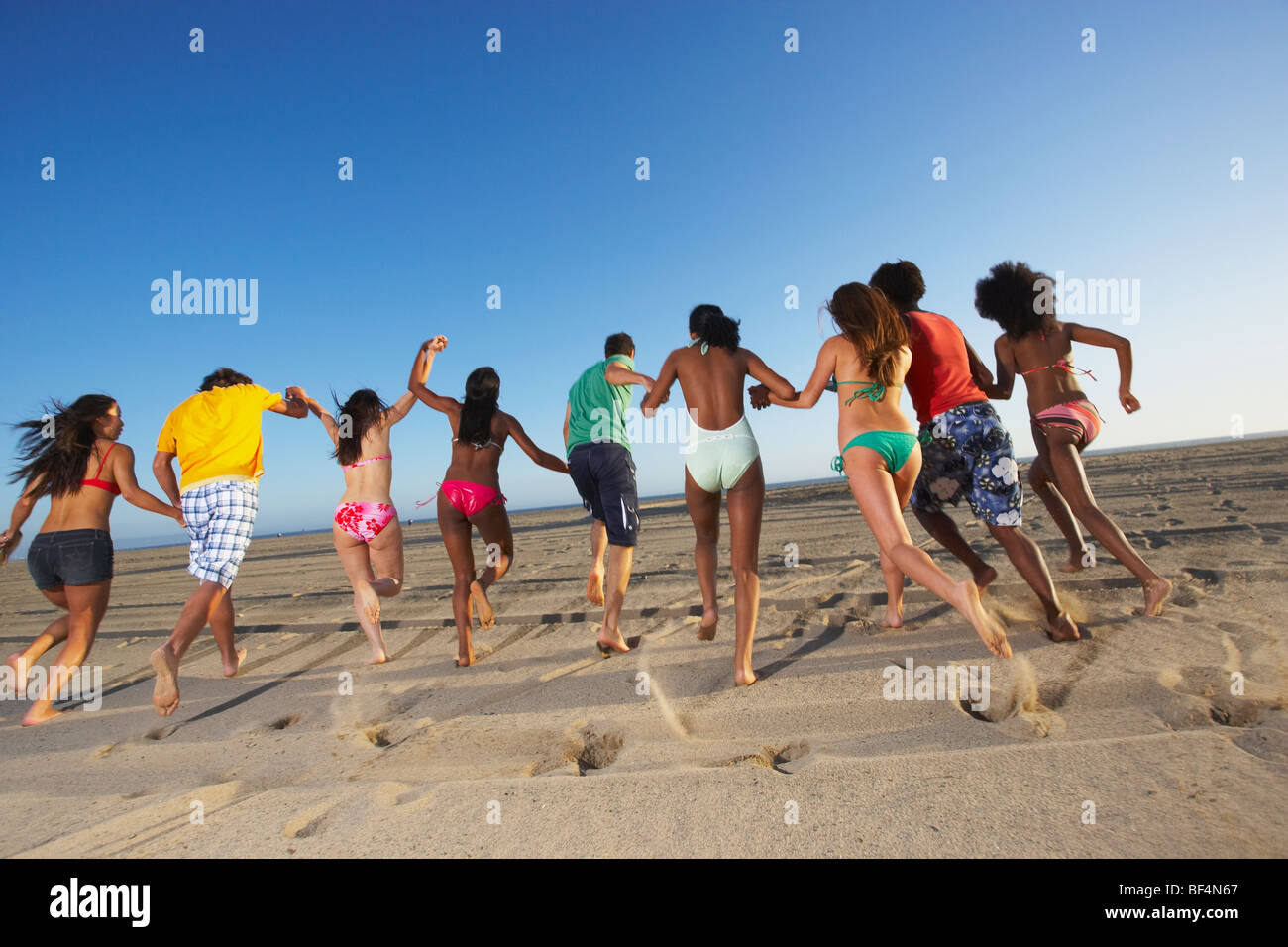 Multi-ethnic group of friends running on beach Stock Photo