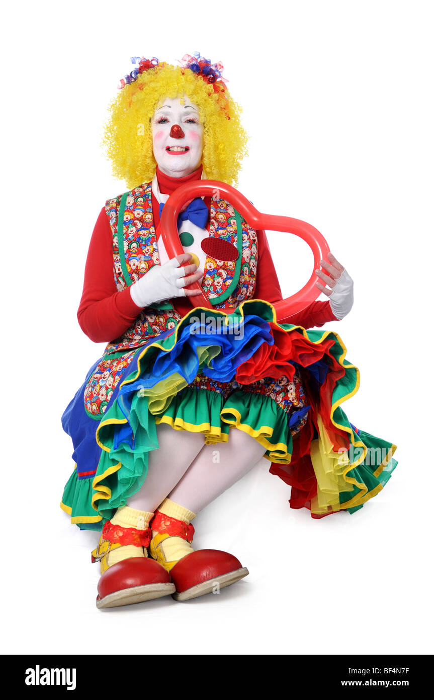 Clown sitting and holding a balloon heart Stock Photo