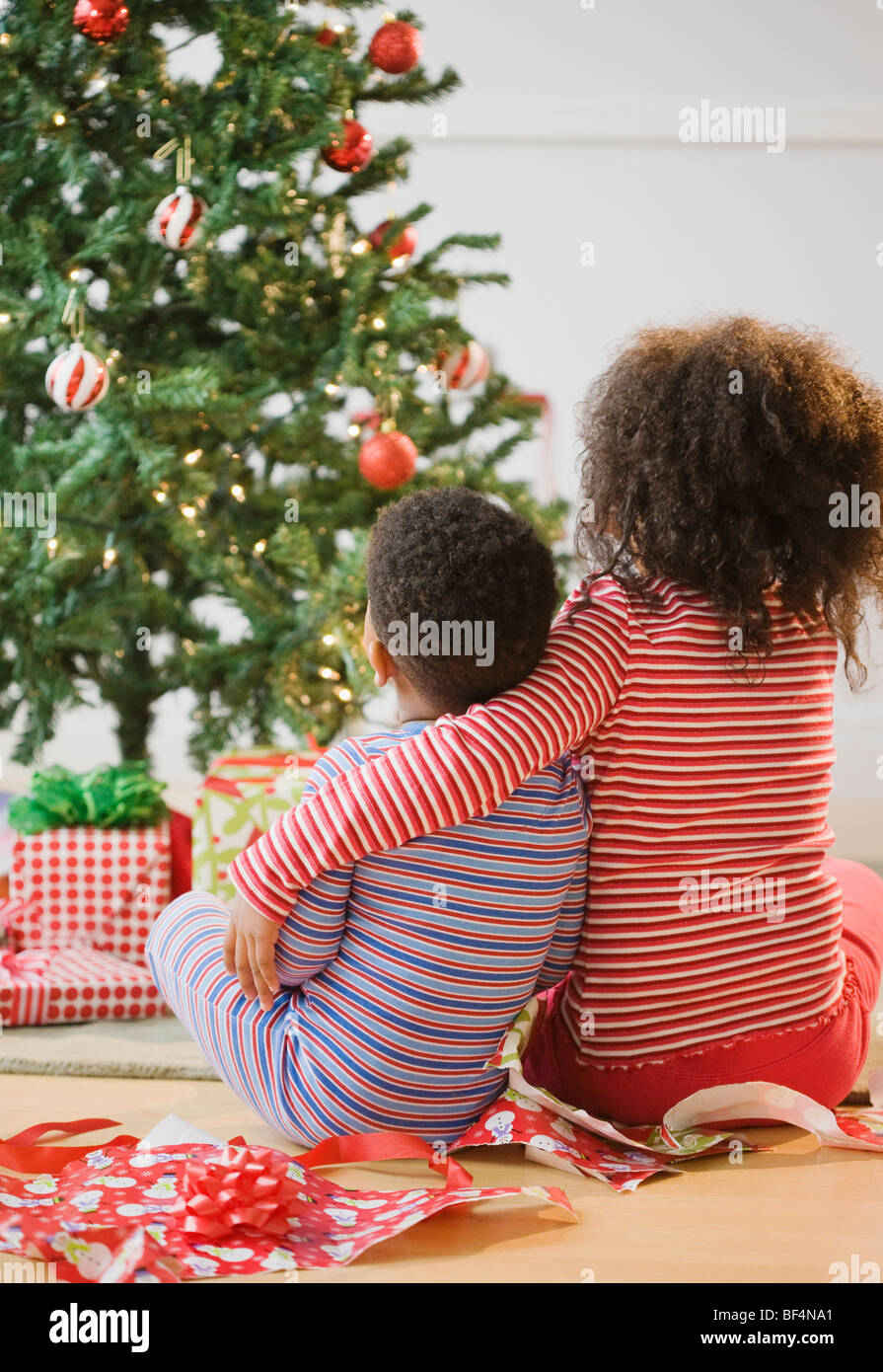 African American brother and sister hugging by Christmas tree Stock Photo