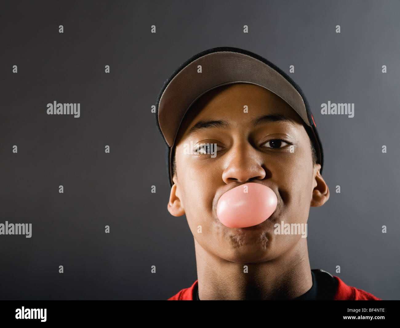 Mixed race baseball player blowing bubble with gum Stock Photo