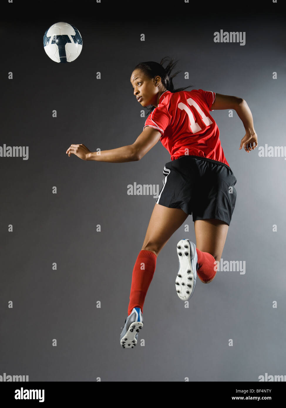 Mixed race soccer player in air with soccer ball Stock Photo