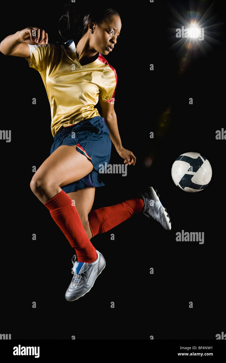 Mixed race soccer player kicking ball in mid-air Stock Photo