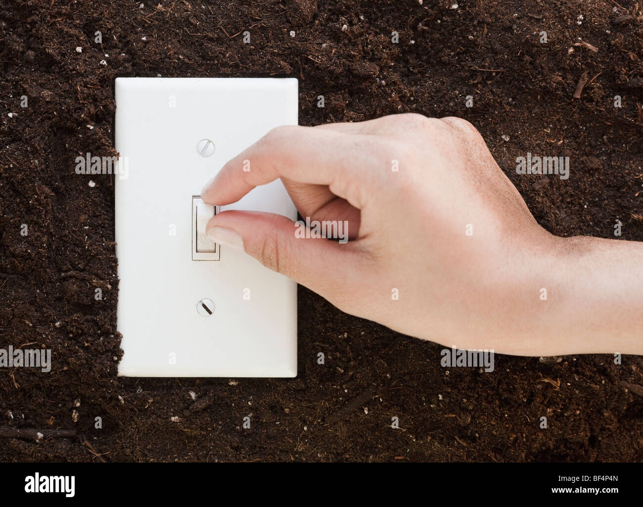 Woman flipping light switch in soil Stock Photo