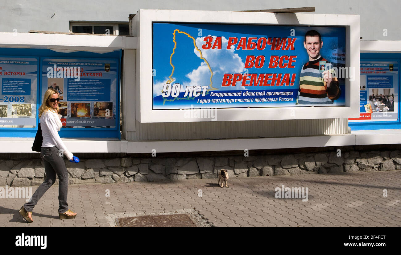 Woman walking dog past billboard advertisement, Russia Stock Photo