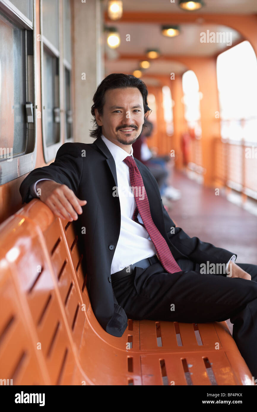 Mixed race businessman smiling on bench Stock Photo