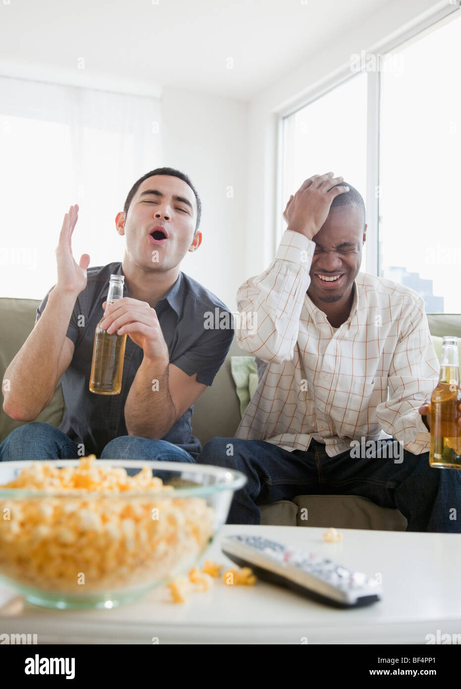 Men drinking beer and watching sports on television Stock Photo