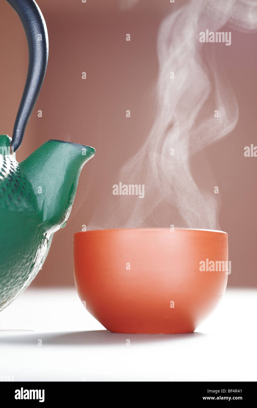 Cast iron teapot with a steaming cup of tea Stock Photo