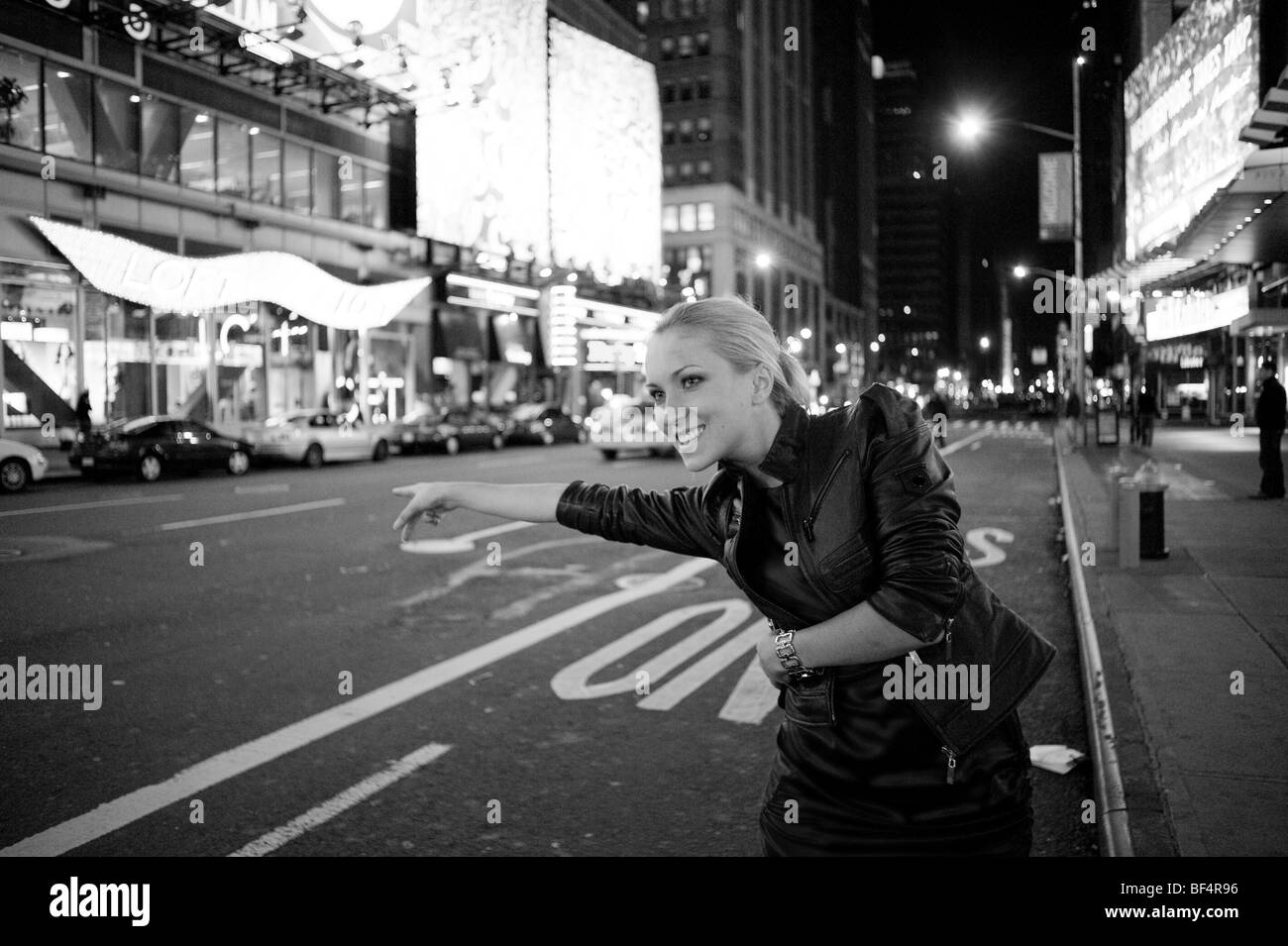 blonde woman hailing taxi, Times Square New York at night Stock Photo