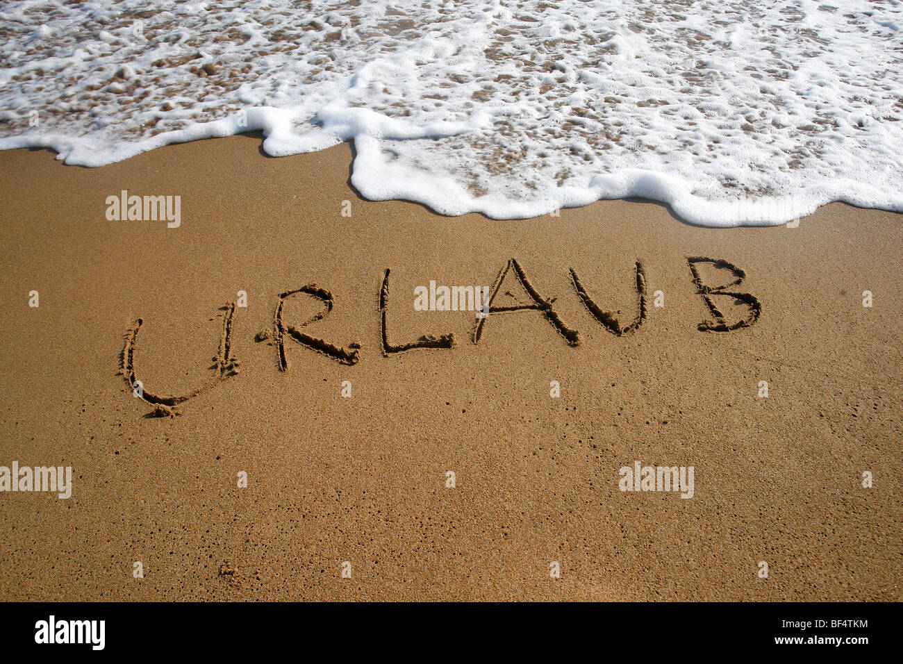 Urlaub, German for Holiday, written in the sand on a beach, Corfu, Greece, Europe Stock Photo