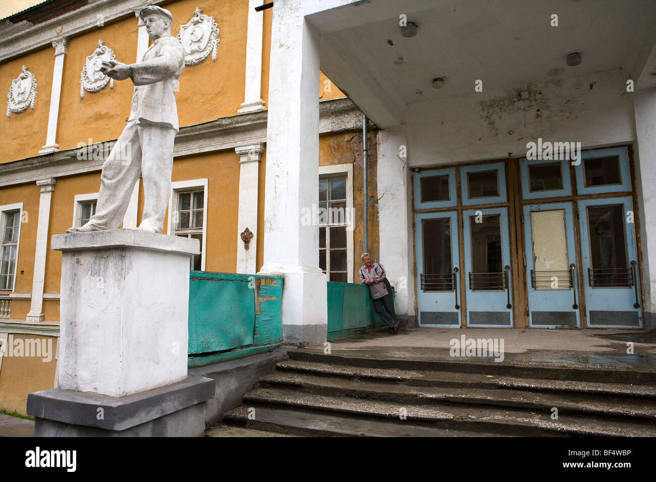 Man at entrance of neglected soviet civic building, Urals, Russia. Stock Photo