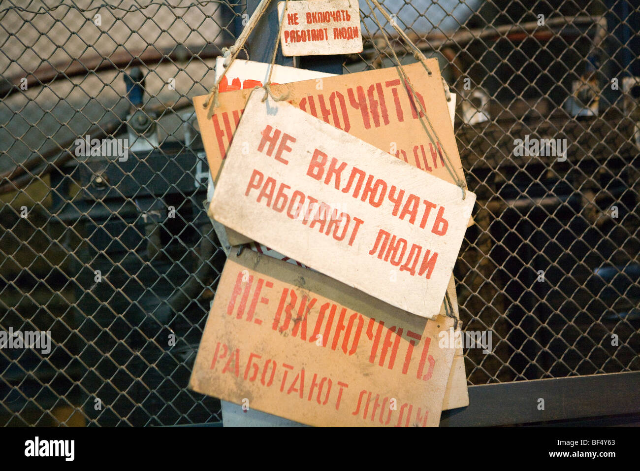 Signs with red Russian words hanging on wire fence in abandoned industrial building, detail, Russia Stock Photo