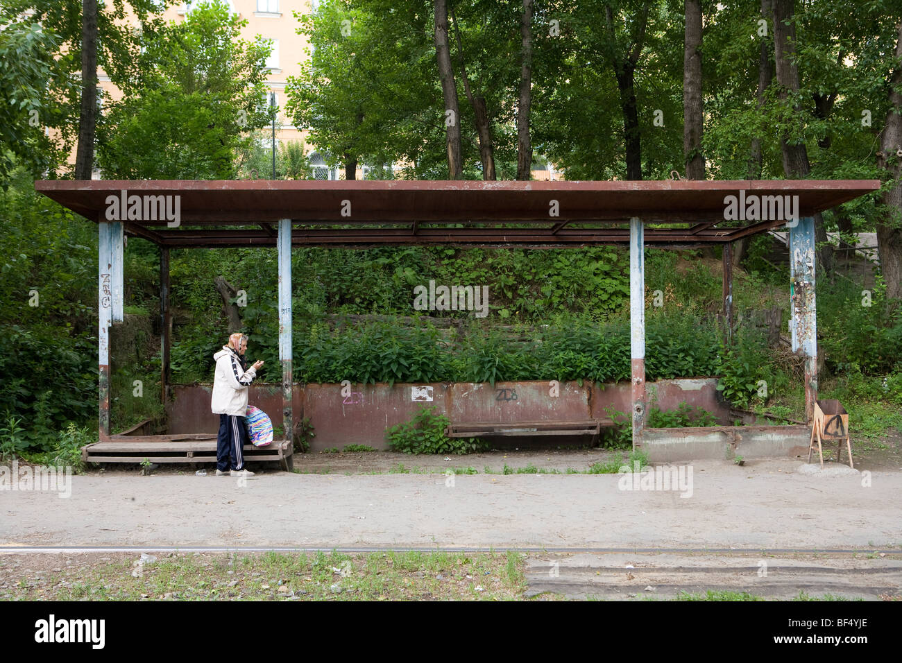 Woman with shopping bag waiting at rural tram station, Tagil, Russia Stock Photo