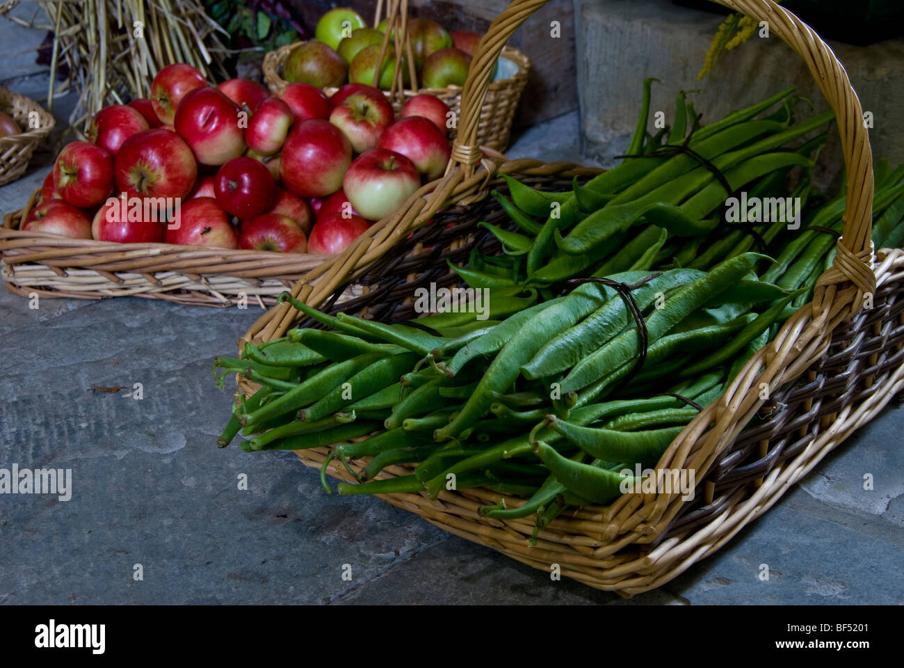 Runner Beans and Apples in a wicker basket on display at a harvest festival. England GB. Stock Photo