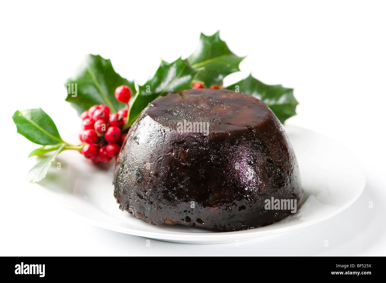 Simple Christmas pudding on white plate and background with holly decoration Stock Photo