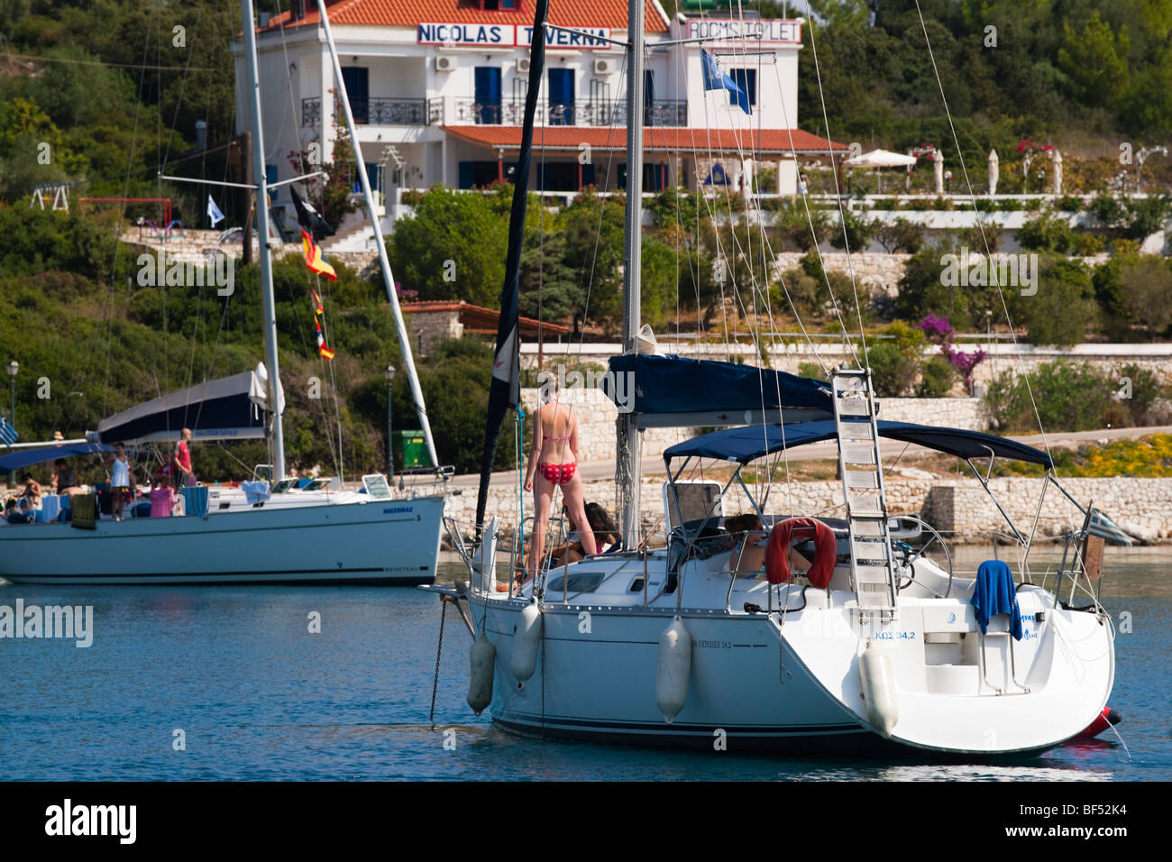 Fiskardo port Kefalonia island Greece - survivor of the 1953 earthquake - cruising yacht with restaurant in background Stock Photo