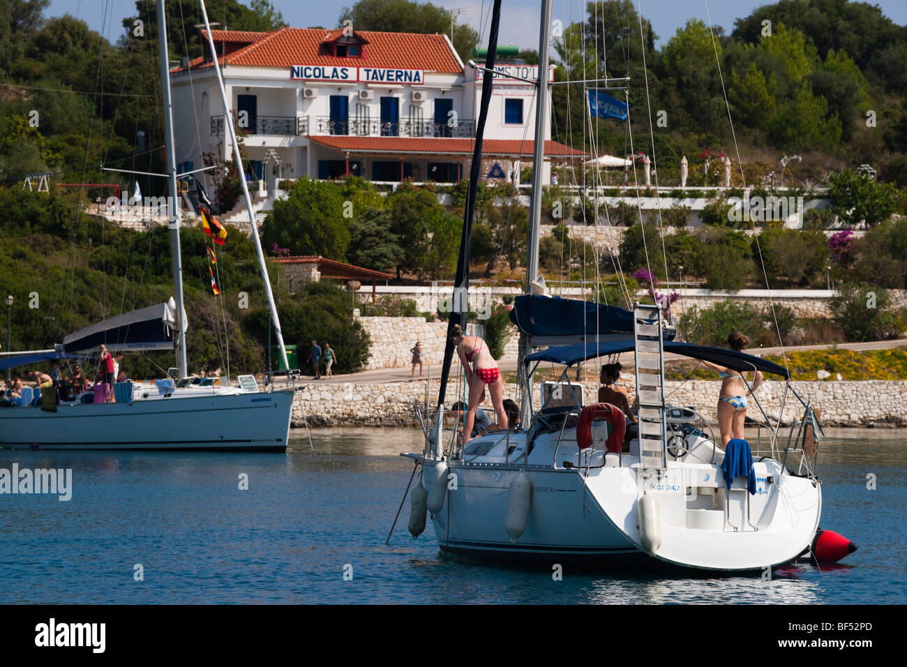 Fiskardo port Kefalonia island Greece - survivor of the 1953 earthquake - cruising yacht with restaurant in background Stock Photo