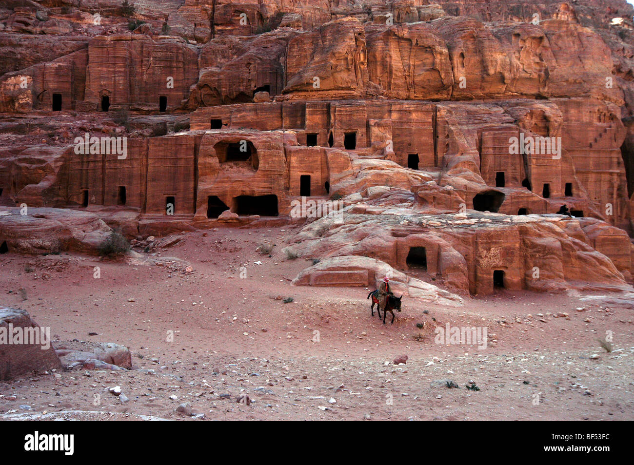 A bedouin rides his horse in front of the tombs on the Street of Facades, Petra, Jordan Stock Photo