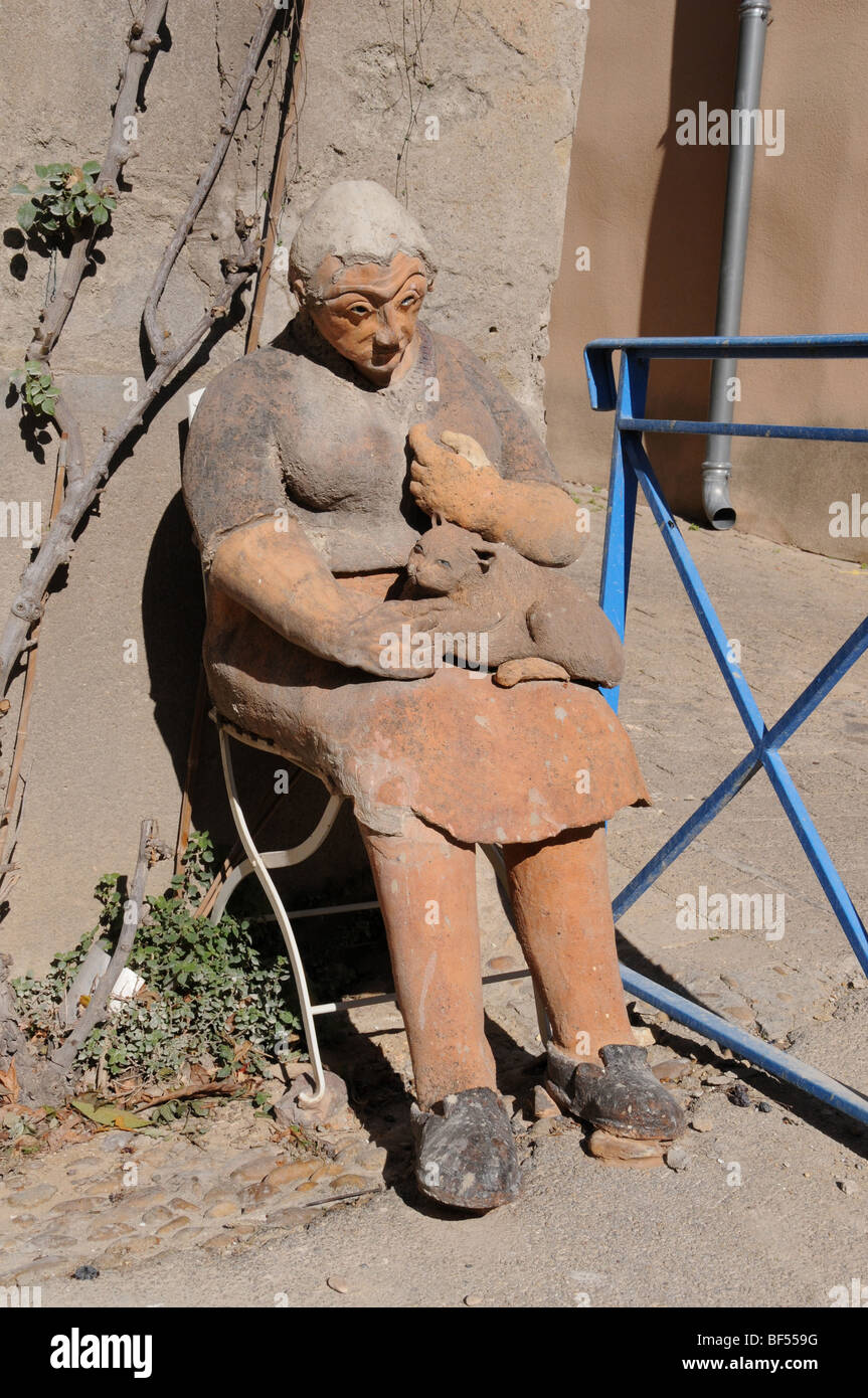 A life-sized terra cotta grandmother sits outside a potter’s studio in the town of St Quentin-la-Poterie. Stock Photo