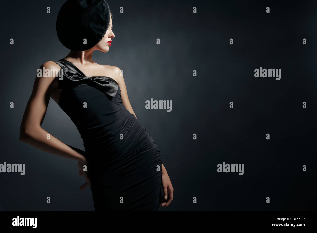 Side portrait of a young woman wearing a black dress and a black hat ...