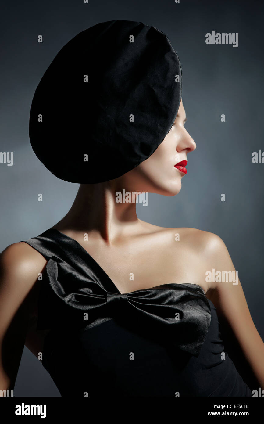 Side portrait of a young woman wearing a black dress and a black hat ...