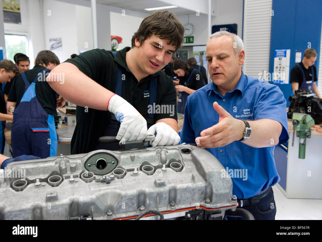 Master explaining to an apprentice while working on an engine in the BMW training center for automotive mechatronics, Munich, B Stock Photo