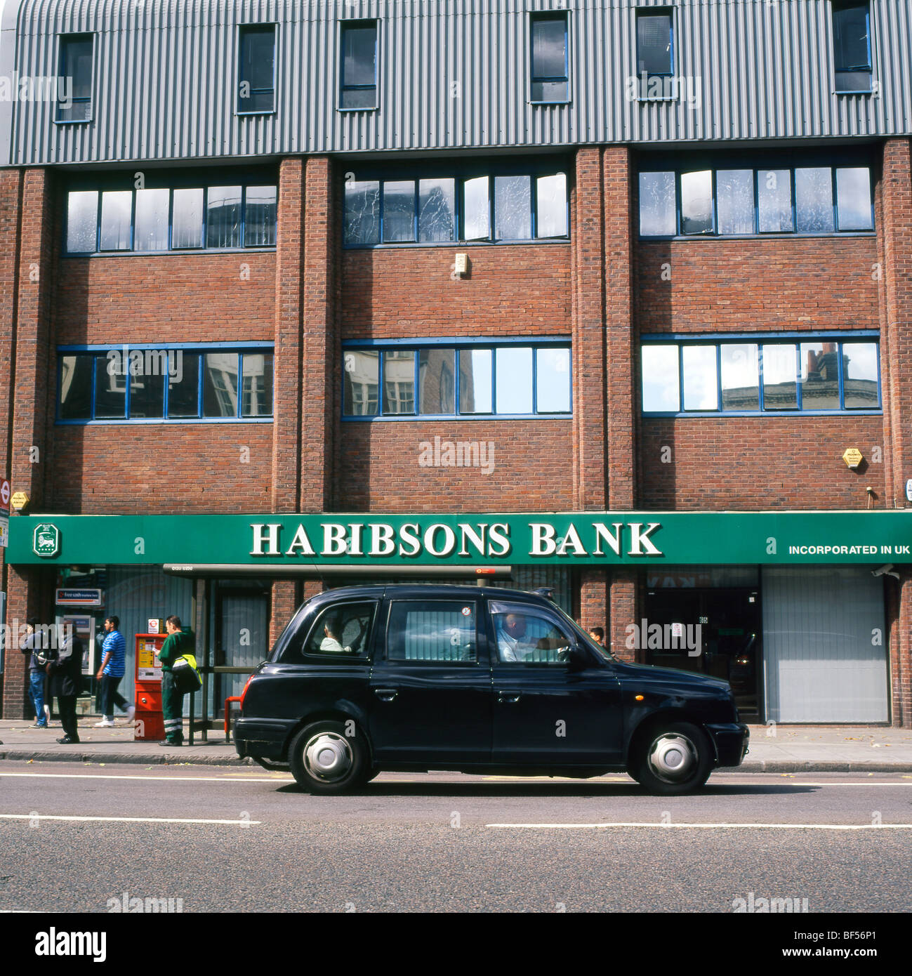 A black taxi cab on Whitechapel High Street driving past Habibsons Islamic Bank London England UK Stock Photo