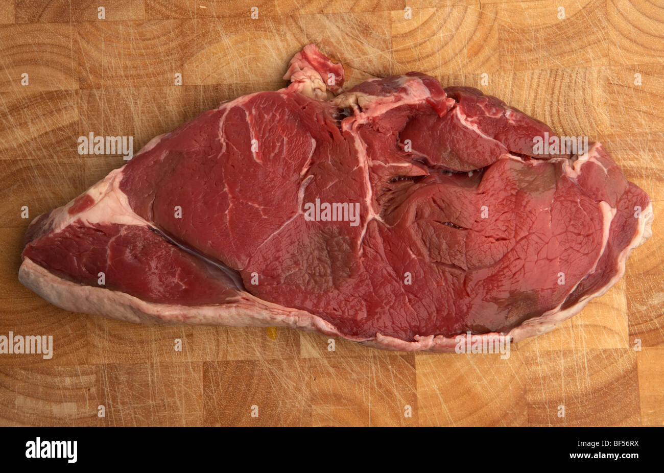 raw slice of chump sirloin steak from organic longhorn irish cows on a wooden butchers block Stock Photo