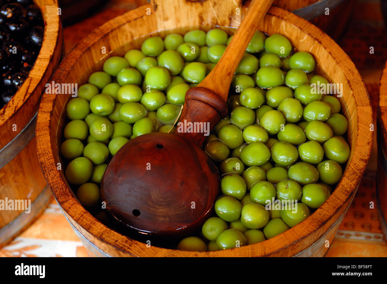 Green olives in a wooden tub with a wooden ladle, Borough Market, 8 Southwark Street, London, England, United Kingdom, Europe Stock Photo