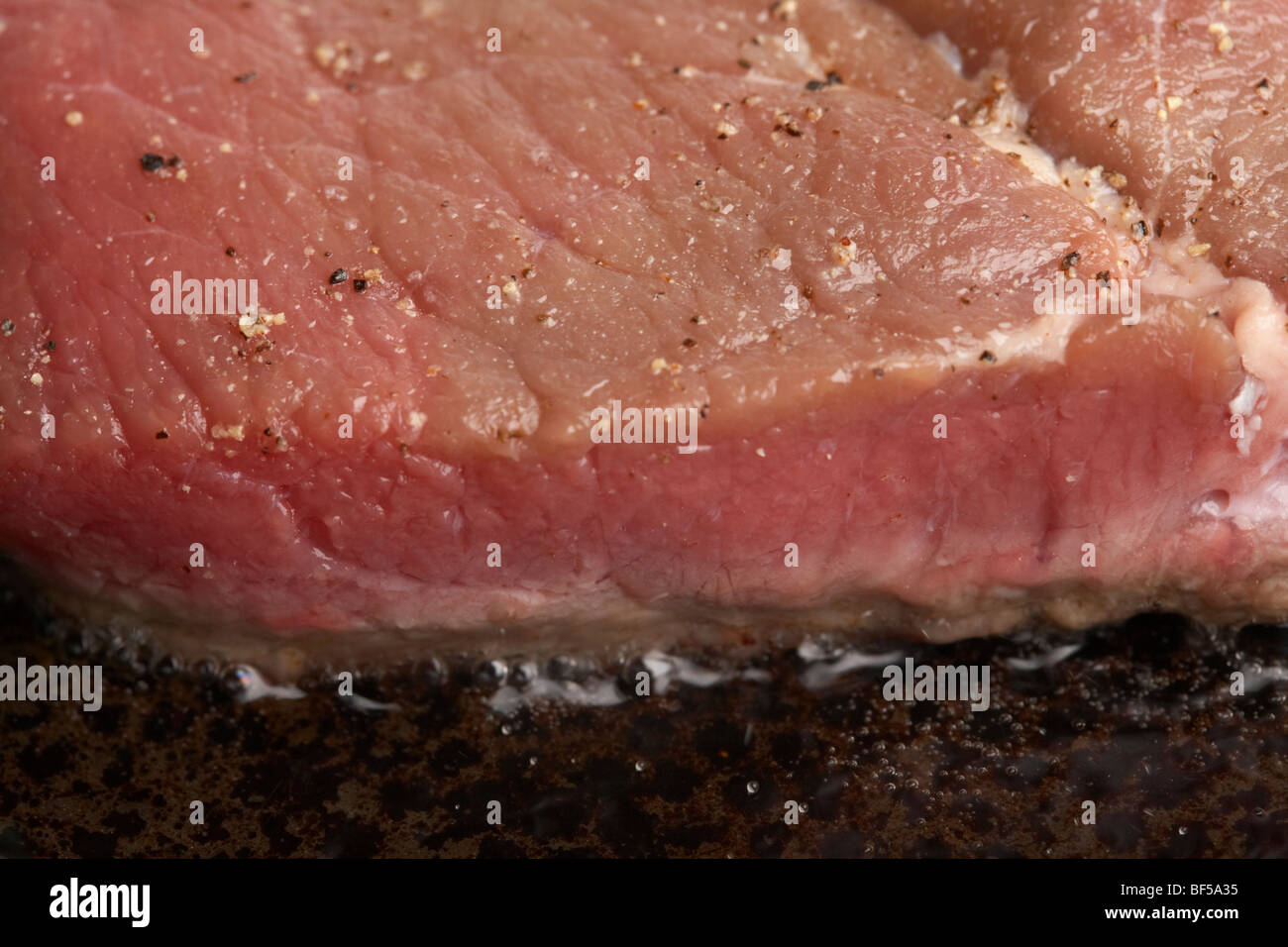 slice of seasoned chump steak from organic longhorn irish cows frying in a frying pan Stock Photo