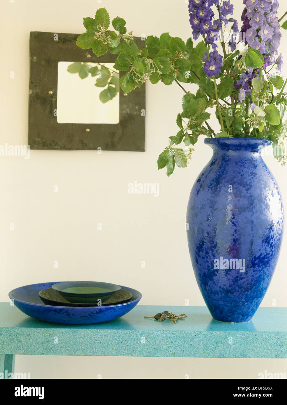 Close-up of blue delphiniums in bright blue vase beside blue bowl on ...