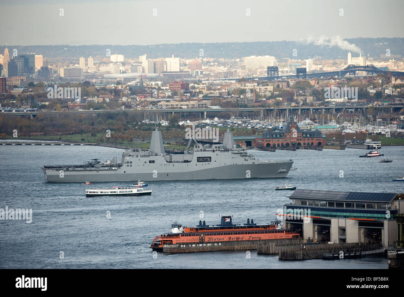 USS New York sails up the Hudson River on her way into New York passing the Staten Island ferry Terminal Stock Photo