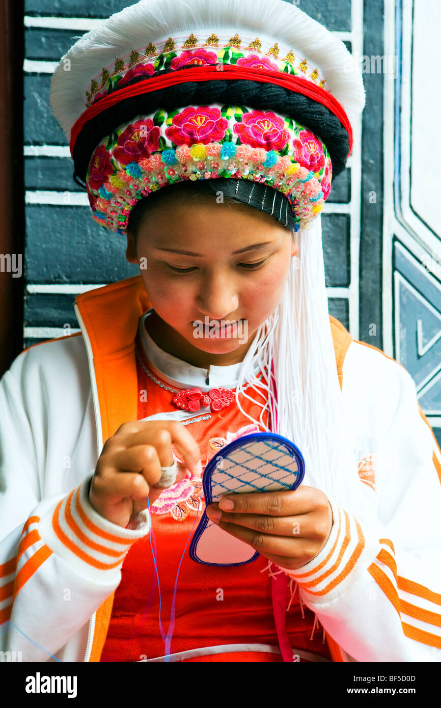 Bai ethnic minority young woman sewing shoe sole, Lijiang, Yunan Province, China Stock Photo