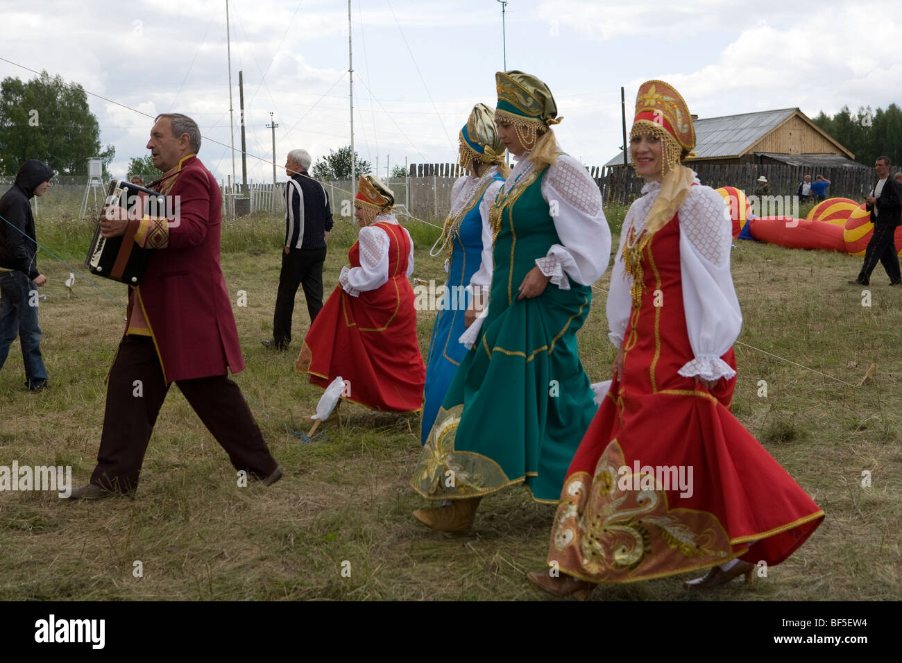 Traditional Russian dancers and accordionist walking to horse racing event, Urals, Russia Stock Photo