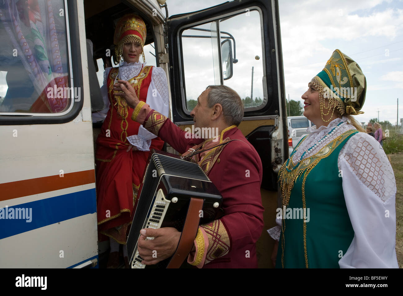 Traditional Russian dancers and accordionist by coach at horse racing event, Urals, Russia Stock Photo