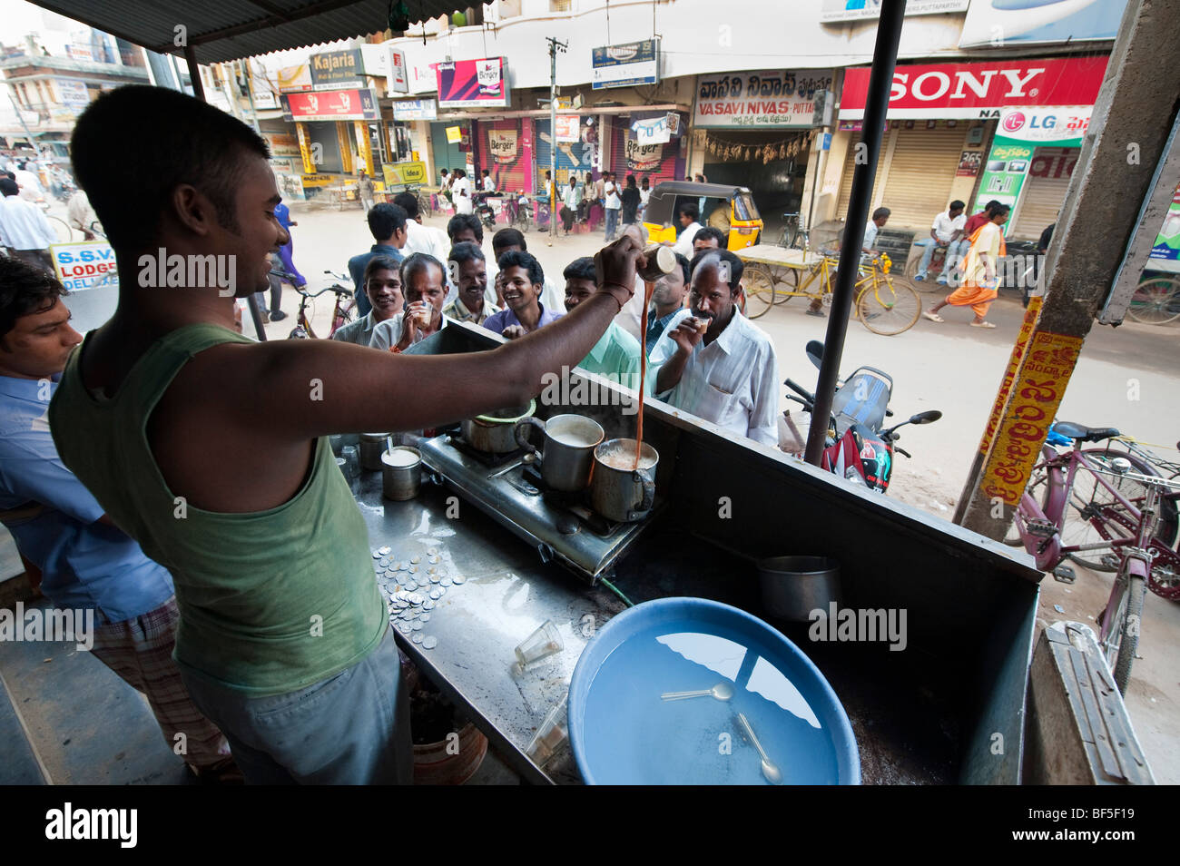 Indian Tea shop owner making and serving tea on an Indian street. Puttaparthi, Andhra Pradesh, India Stock Photo