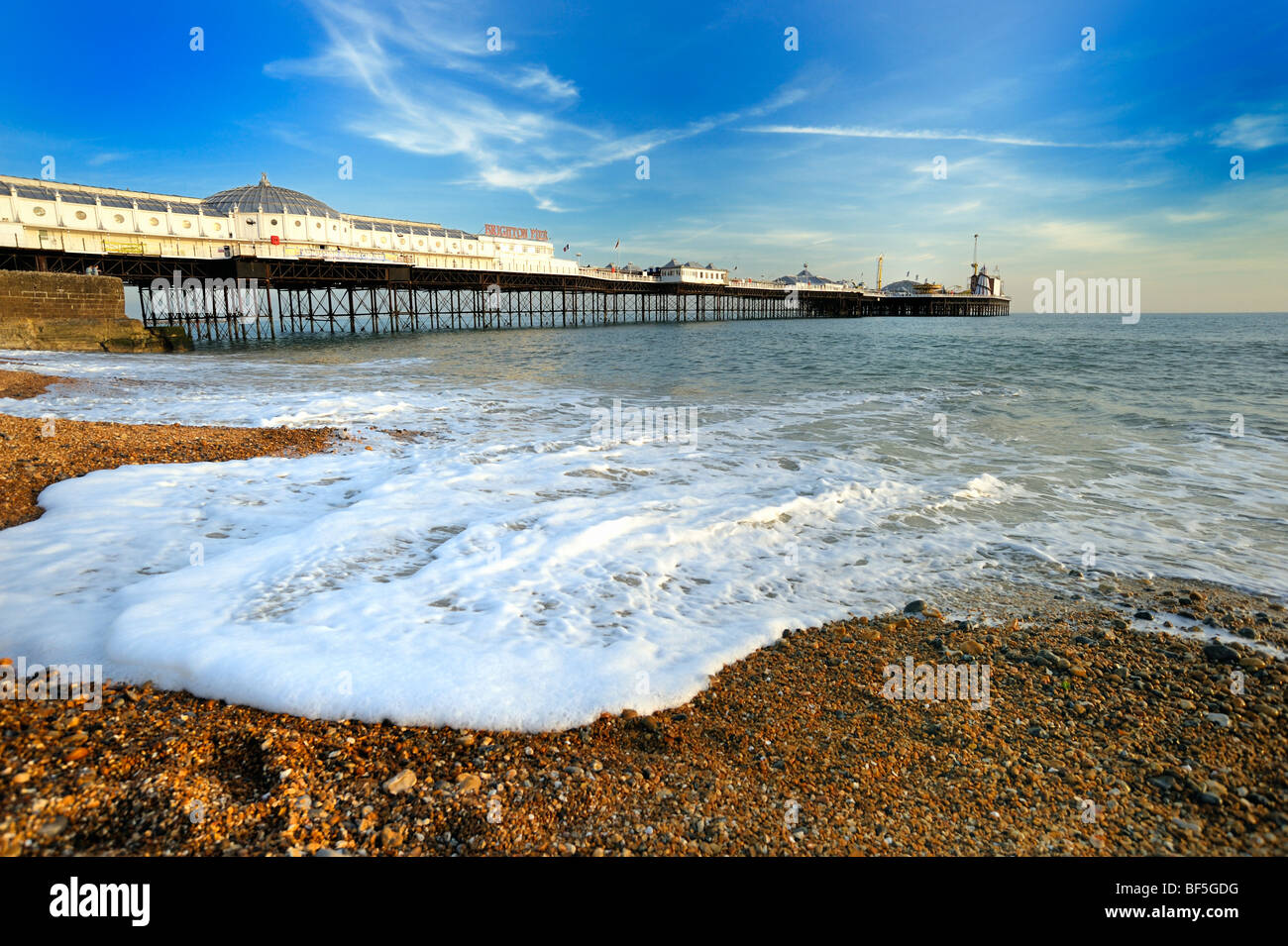 Brighton Pier with foaming waves in the foreground Stock Photo