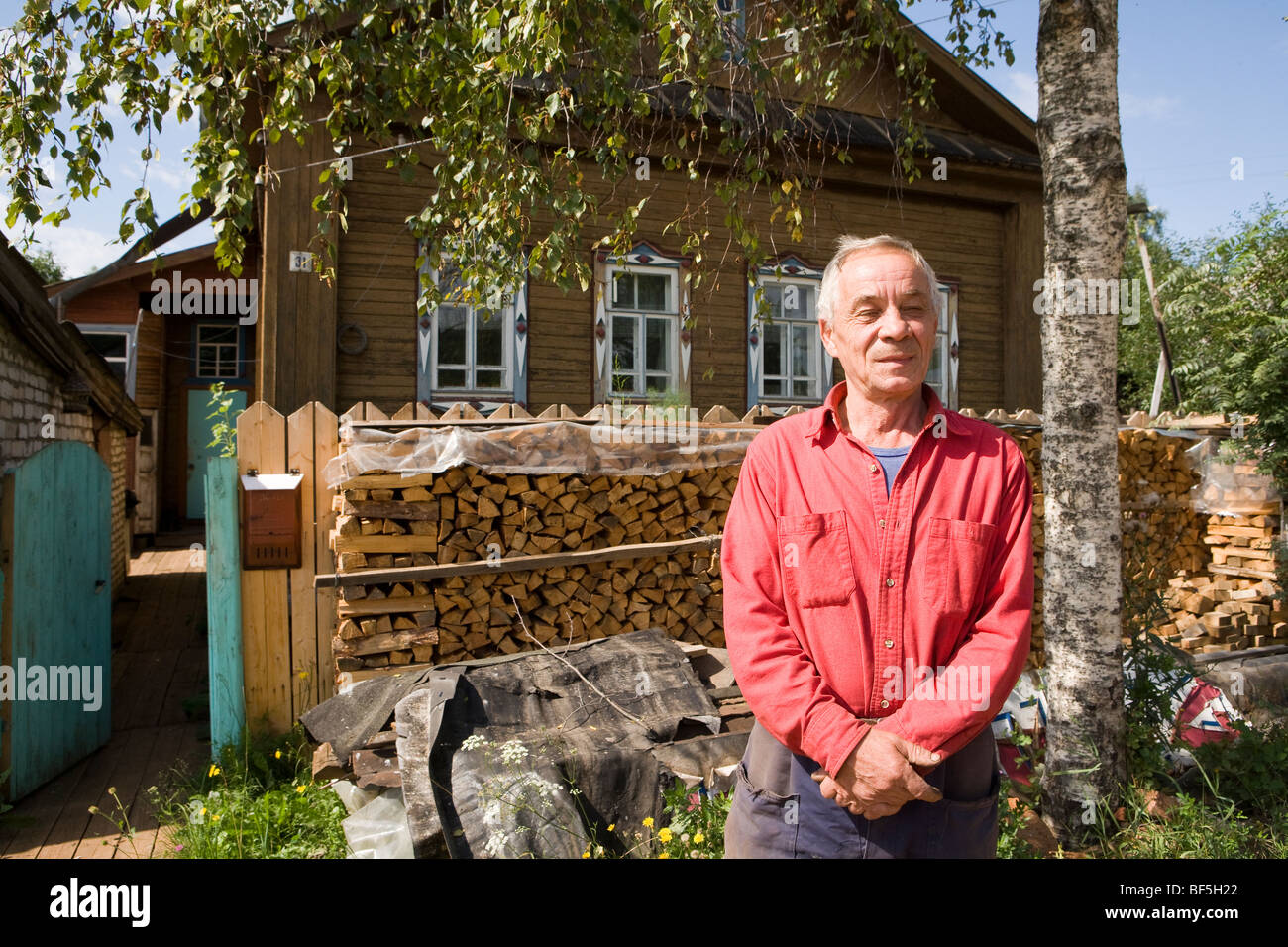 Man in dacha (second home) garden with stacked logs, portrait, Kirov, Kirov Oblast, Russia Stock Photo