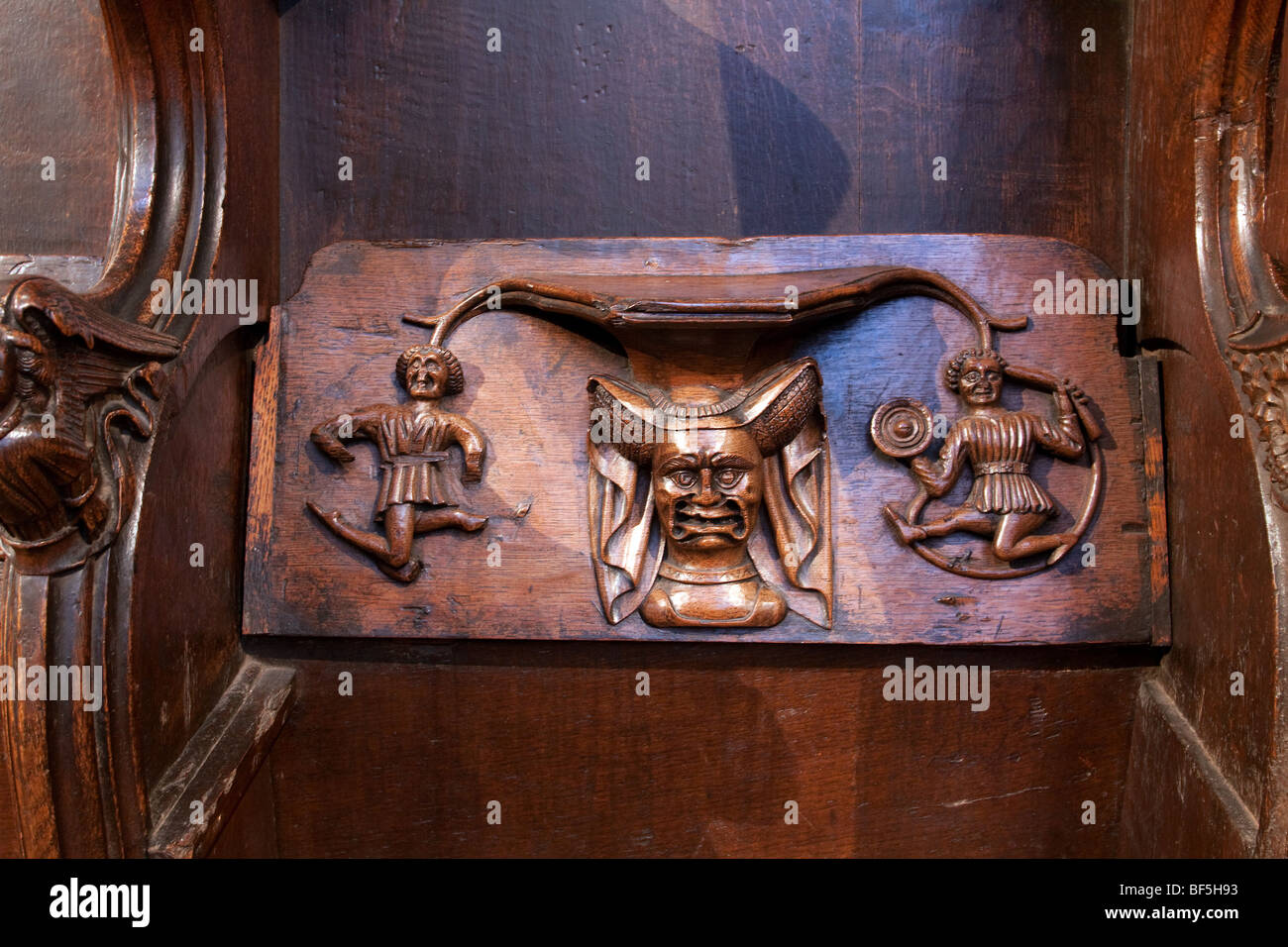 Carved wooden misericord in Saint Laurence Church Ludlow Shropshire showing a grinning 14 th Century 'scold' Stock Photo